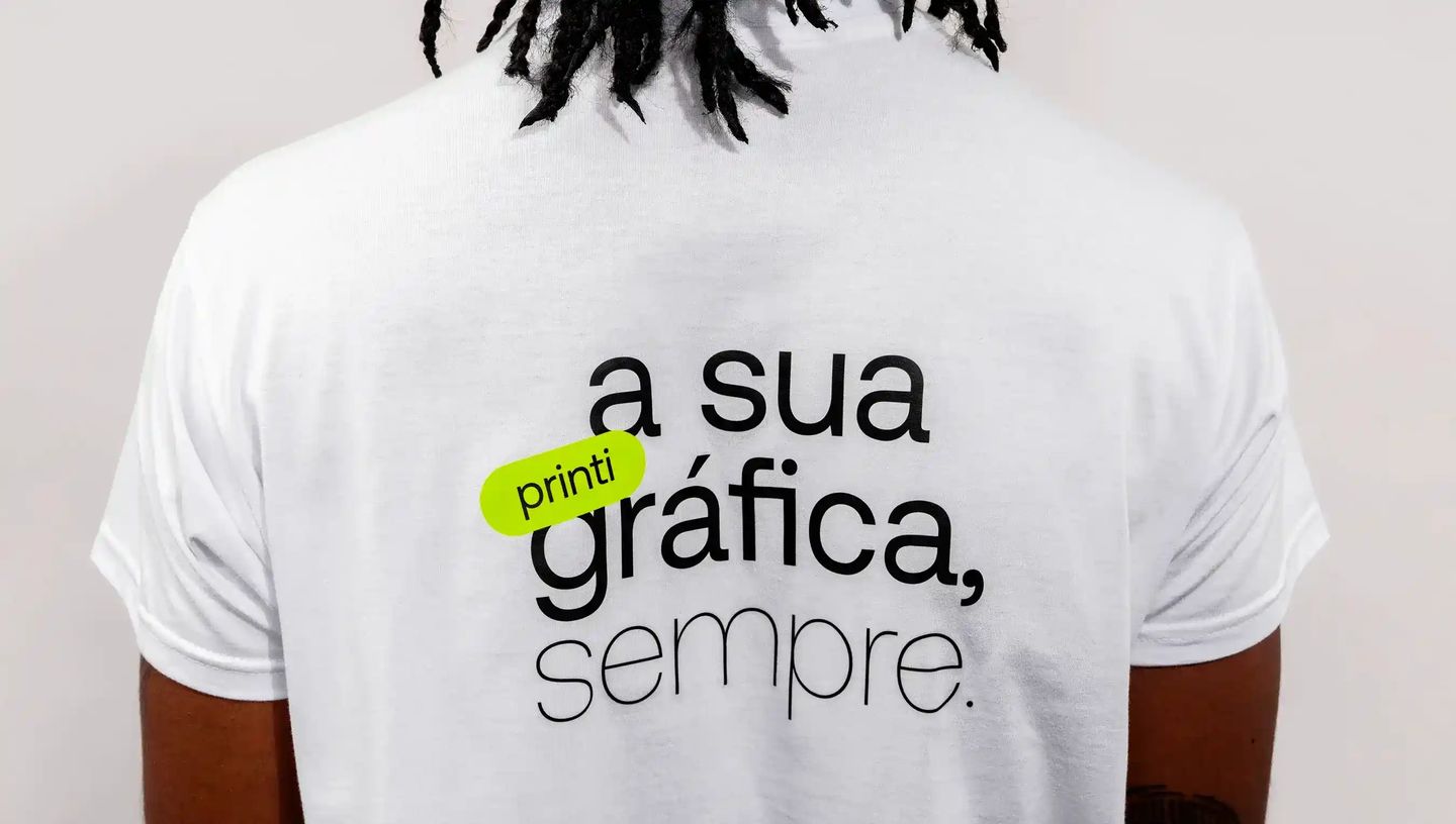 Camiseta branca personalizada com estampa tipográfica e frase “a sua gráfica, sempre”.