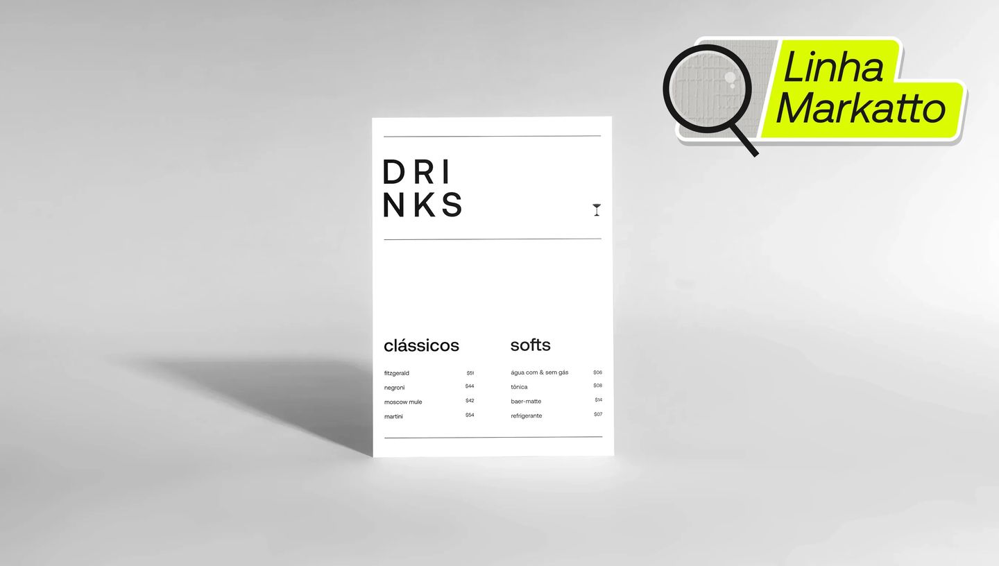 Cardápio de papel sem dobra da linha Markatto em papel texturizado branco, exibindo layout minimalista com o título “DRINKS” e lista de bebidas clássicas e soft drinks. O material está posicionado em pé sobre fundo neutro