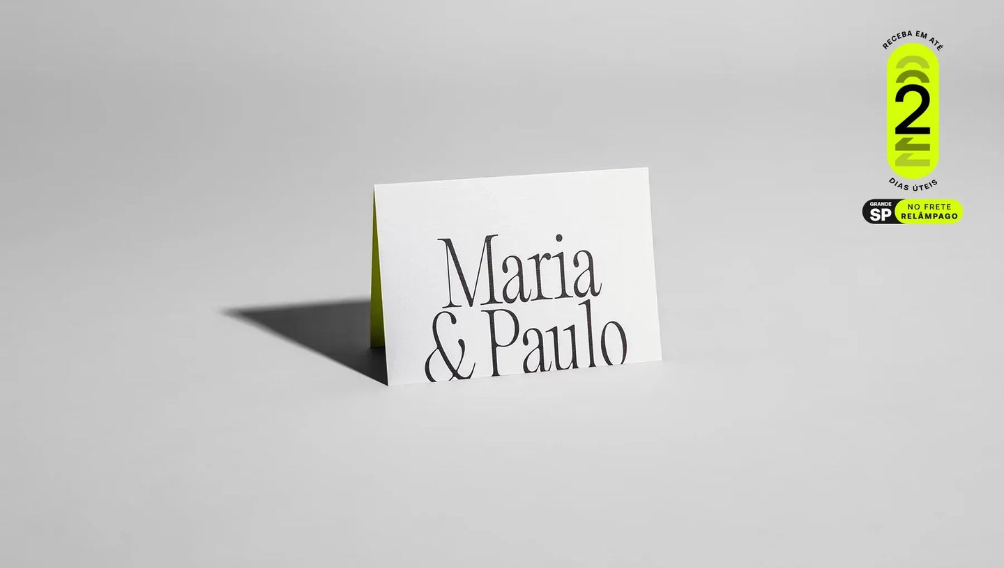 Convite de casamento minimalista em papel branco fosco com os nomes "Maria & Paulo" impressos em tipografia elegante preta, levemente aberto revelando o interior verde-limão sobre fundo cinza claro com selo de entrega em 2 dias úteis para São Paulo