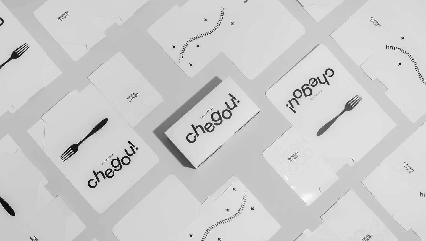 Embalagens personalizadas para combos de alimentos exibidas abertas e montadas sobre fundo claro, com design minimalista em preto e branco e frase “sua comida chegou”