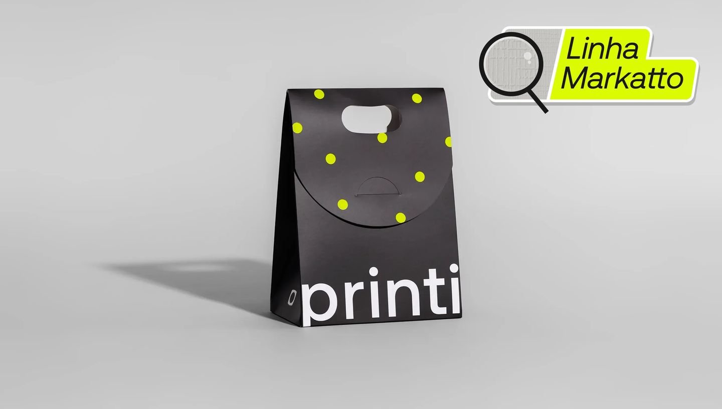Sacola de papel personalizada da linha Markatto da Printi, na cor preta com estampa de pontos amarelos e logo “printi” em destaque, apresentada sobre fundo neutro para evidenciar o design moderno da embalagem utilizada para presentes, kits promocionais e 