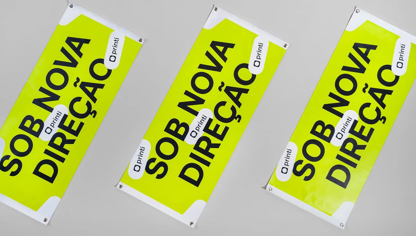 Faixa personalizada verde neon com a frase 'Sob Nova Direção' e logotipos da Printi.