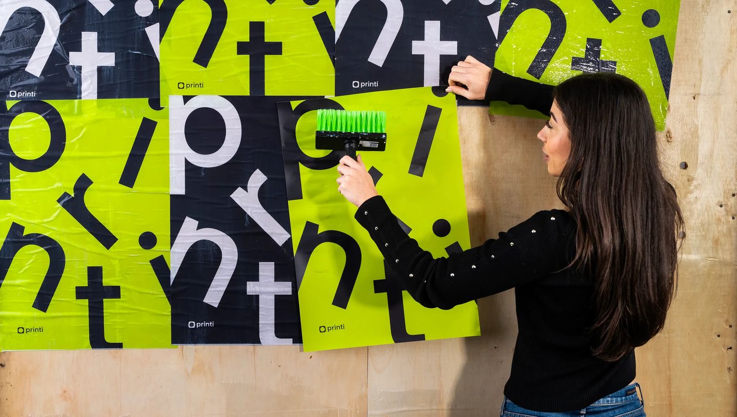 Aplicação de lambe-lambe personalizado em parede de madeira com cores preto e verde neon vibrantes.