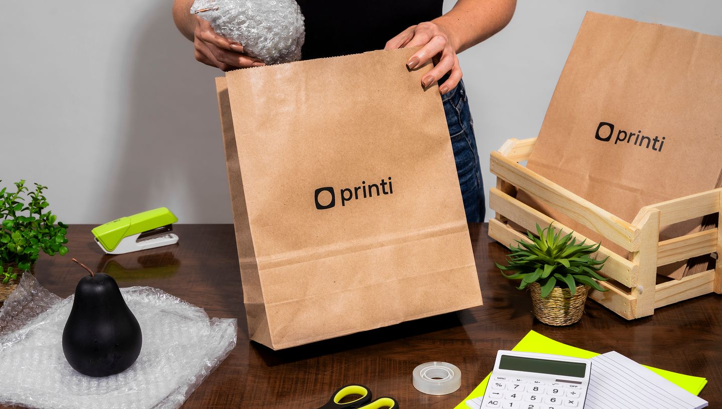 Pessoa embalando produto em saco de papel kraft com logo da Printi