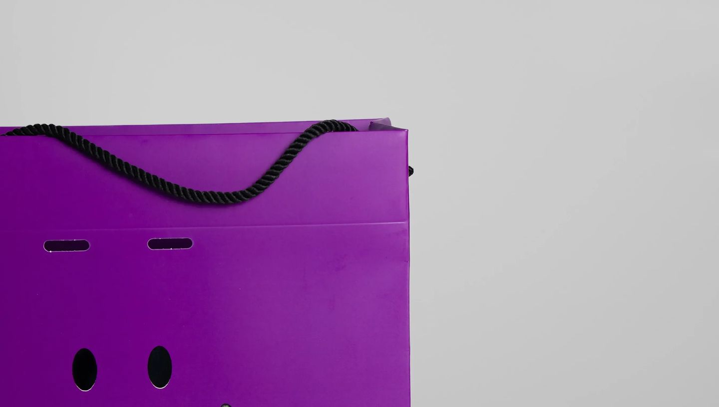 Sacola de papel personalizada na cor roxa com alça de corda para embalagem de produtos.