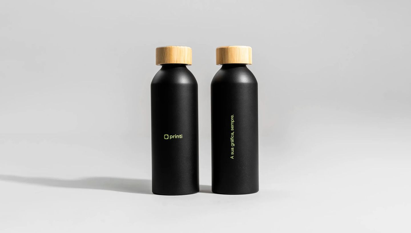 Squeeze térmico personalizado preto com acabamento fosco e tampa de bambu, exibido em duas posições com logo Printi e frase vertical “A sua gráfica, sempre.”, fotografado em estúdio com fundo neutro para destacar o design minimalista do produto.