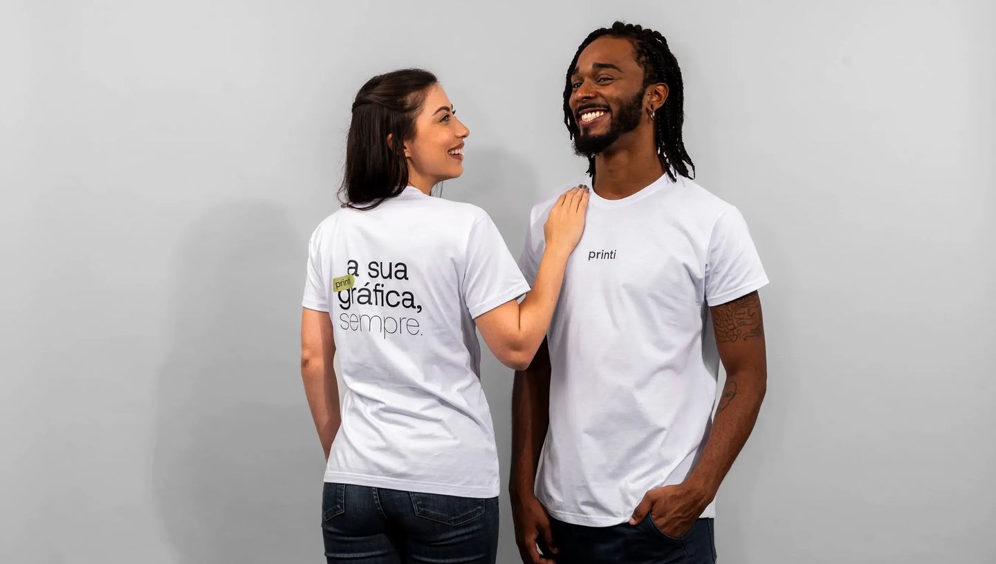 Camisetas personalizadas com logotipo e frase estampada, usadas por duas pessoas como uniforme corporativo.