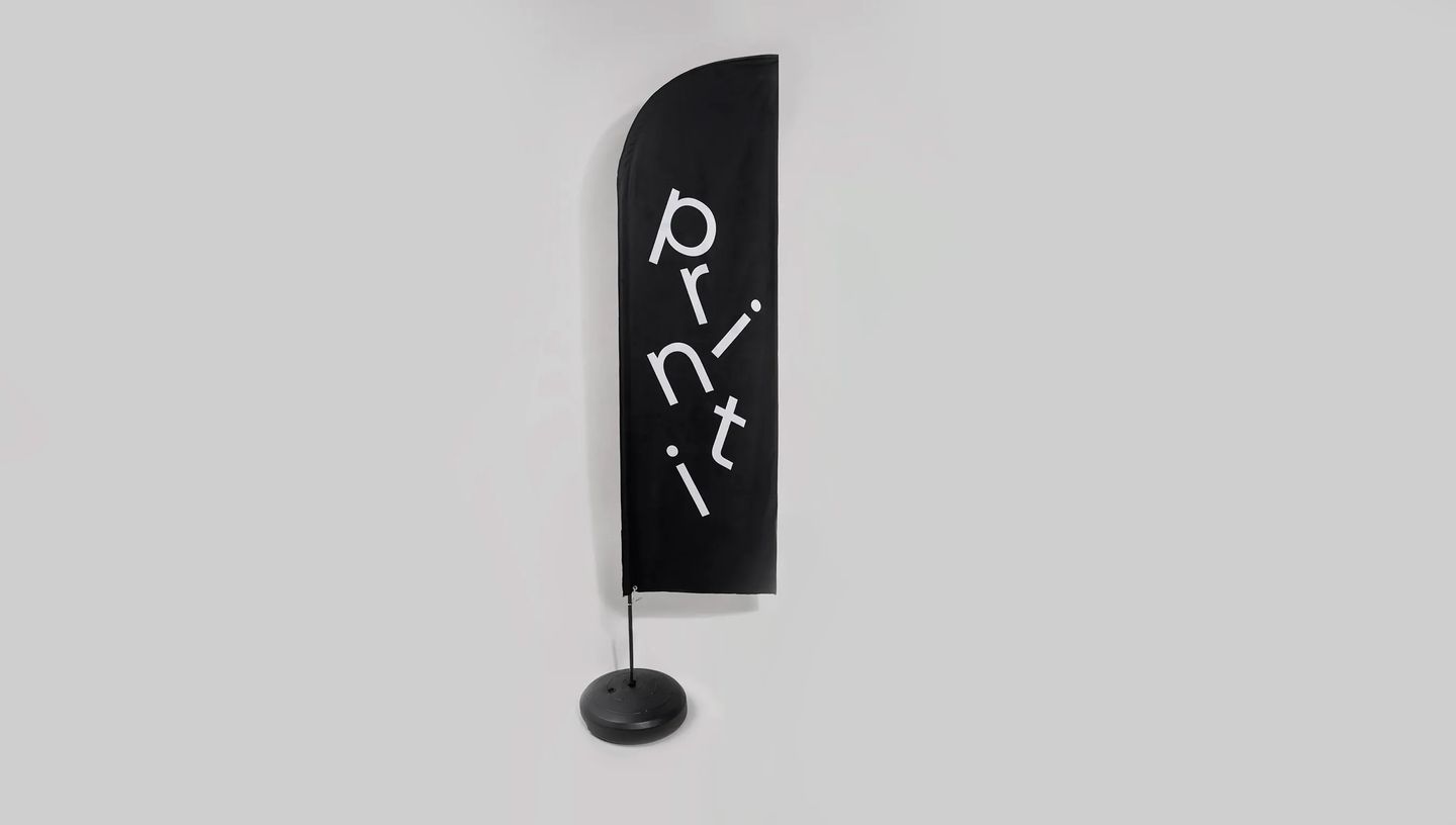 Wind banner personalizado vertical preto com logo Printi montado em base para sinalização externa.