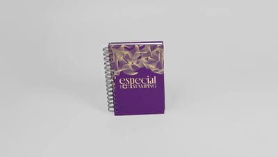 Agenda personalizada com capa roxa, detalhes em hot stamping dourado e encadernação espiral metálica.