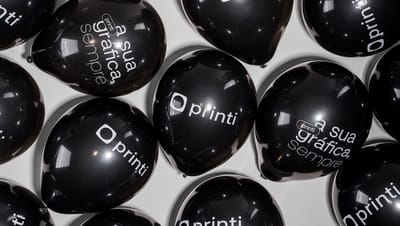 Vários balões personalizados pretos com a marca Printi e a frase 'a sua gráfica, sempre'.