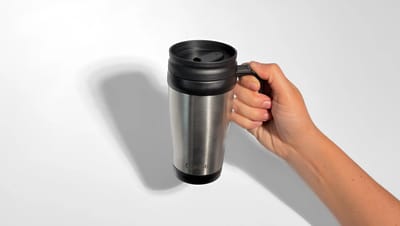 Pessoa segurando caneca para viagem personalizada de inox, na cor preta.