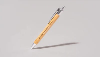 Caneta ecológica personalizada com corpo em bambu natural e detalhes metálicos prateados, com gravação da marca Printi ao longo do corpo, exibida inclinada sobre fundo neutro, representando um brinde corporativo sustentável ideal para ações promocionais, 
