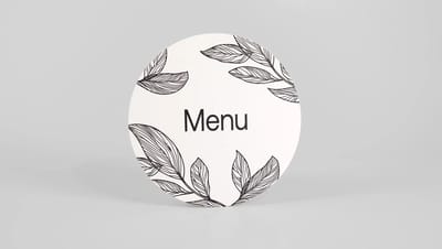 cardápio redondo na cor branca escrito menu e com folhas envolta 