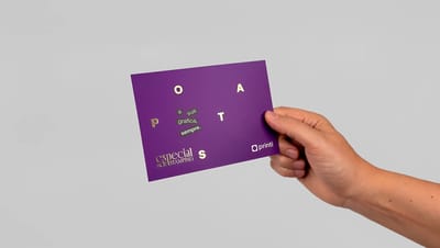 Cartão postal personalizado roxo com detalhes em hot stamping dourado segurado por uma mão.