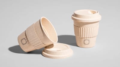 Copo para viagem personalizado de 380ml em tom bege, com tampa e pegador, sendo um copo exibido deitado e o outro em pé em fundo liso e branco.