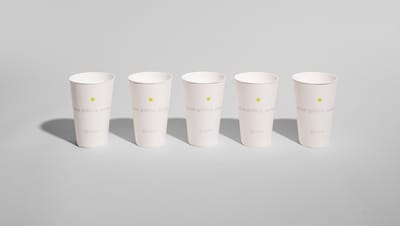 Cinco unidades de Copo in Mold personalizadas com logo da Printi, alinhadas sobre fundo cinza neutro.