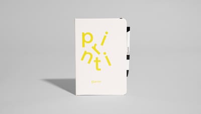 Caderneta com caneta personalizada na cor branca com o nome "Printi" em amarelo.