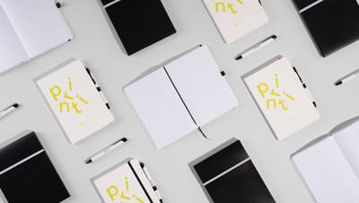 Várias cadernetas com canetas personalizadas.