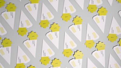 Embalagens pirâmides desmontadas, nas cores branco e amarelo.