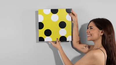  Mulher segurando banner com moldura estampado com bolinhas brancas e pretas sobre fundo amarelo
