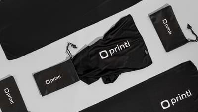 Toalha esportiva em PET com bolsa, ambas na cor preta com logo da Printi.