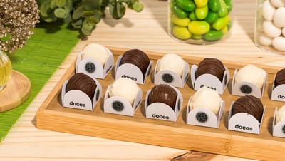 Embalagem para doces com doces em mesa de madeira com vários potes e plantas ao redor