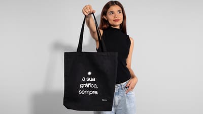 Mulher segurando uma ecobag preta de algodão reciclado com o slogan da Printi.
