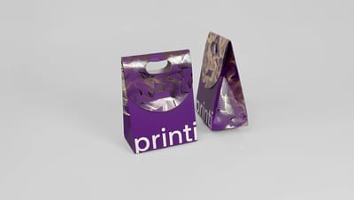 Duas embalagens tipo sacola roxas personalizadas com acabamento premium em hot stamping dourado.
