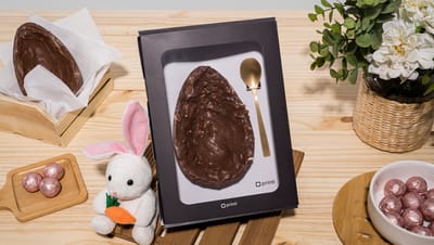 Embalagem para ovo de colher com visor transparente exibindo ovo de Páscoa com colher dourada em mesa decorada