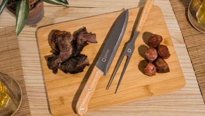 Kit Churrasco Cubat da Printi em uso com tábua de madeira, carne assada e utensílios com cabo de madeira