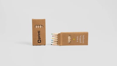 Lápis de cor em caixa de papel kraft personalizada com logotipo e slogan em design sustentável.
