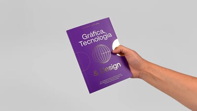 Mão segurando livreto personalizado roxo com título 'Gráfica, Tecnologia & Design' e acabamento premium.