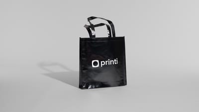 Imagem de sacola em TNT Laminado preta com logo da Printi em fundo cinza