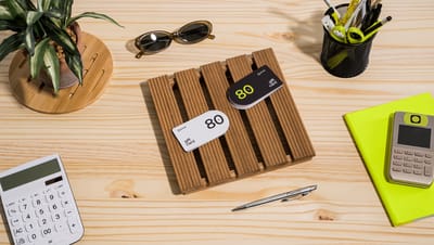 Vista superior de mesa com cartões de vale presente personalizados sobre suporte de madeira.