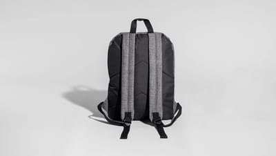 Mochila para notebook personalizada da Printi exibida pela parte traseira, com alças acolchoadas e design ergonômico em tecido cinza e preto sobre fundo neutro