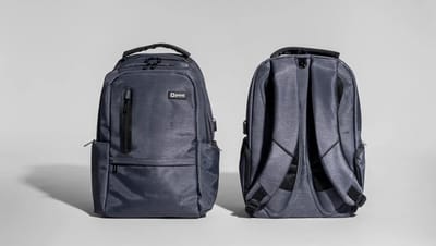 Mochila para notebook personalizada da Printi em tecido cinza, exibida pela frente e pela parte traseira, com compartimentos com zíper, alças acolchoadas e design ergonômico
