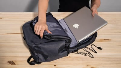 Pessoa colocando notebook em mochila para notebook personalizada da Printi com compartimento acolchoado e porta USB externo