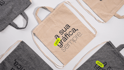 Mochilas saco personalizadas em algodão reciclado nas cores bege e cinza com estampa “a sua gráfica, sempre.” da Printi