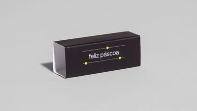 Rótulo de Bis preto com acabamento brilhante, frase “feliz páscoa” centralizada e pontos amarelos decorativos