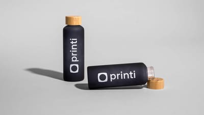 Squeeze de vidro personalizado da Printi com tampa de bambu, exibido em duas posições sobre fundo neutro