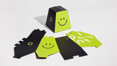 Urna personalizada de papelão da Printi em cores preta e verde neon com desenho de um rosto sorridente, mostrada desmontada e montada