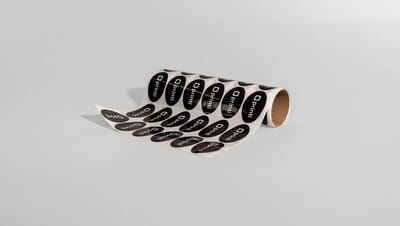 Rolo de adesivos ovais personalizados com impressão em preto e branco, ideais para etiquetas de produtos, embalagens e identificação de marca.