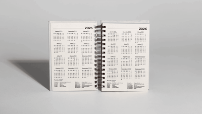 Agenda permanente personalizada aberta exibindo calendários de 2025 e 2026 em páginas pautadas.