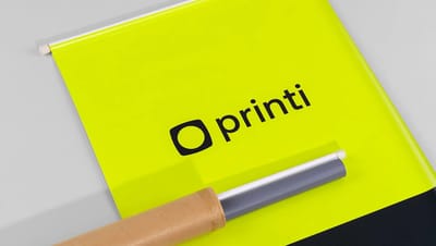 Detalhe de banner em lona com acabamento em bastão e cordão, exibindo o logotipo da Printi em lona fosca de alta qualidade.