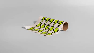 Cartela de adesivos com corte especial em formato de raio na cor verde limão, exibida em um rolo de papel sobre fundo cinza neutro.