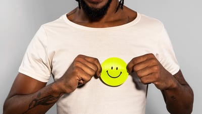 Homem segurando adesivo redondo personalizado verde limão com ícone de sorriso, destacando aplicação em vestuário e brindes promocionais.