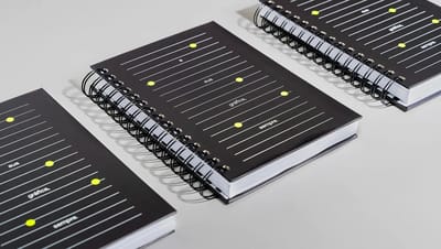 Composição de agendas permanentes da Printi em diferentes ângulos, exibindo capas coloridas, sistema de fechamento resistente.