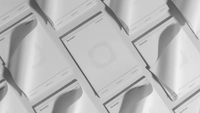 Composição de diversos blocos de notas personalizados espalhados sobre superfície neutra, destacando design clean.
