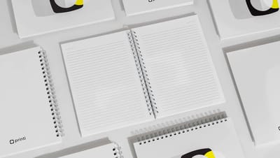Visão interna de caderno personalizado Printi com páginas pautadas e acabamento em espiral wire-o prata, ideal para escrita e organização.