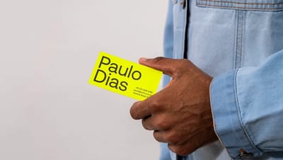 Mão segurando cartão de visita amarelo personalizado com tipografia moderna, destacando a legibilidade e o acabamento premium da Printi.